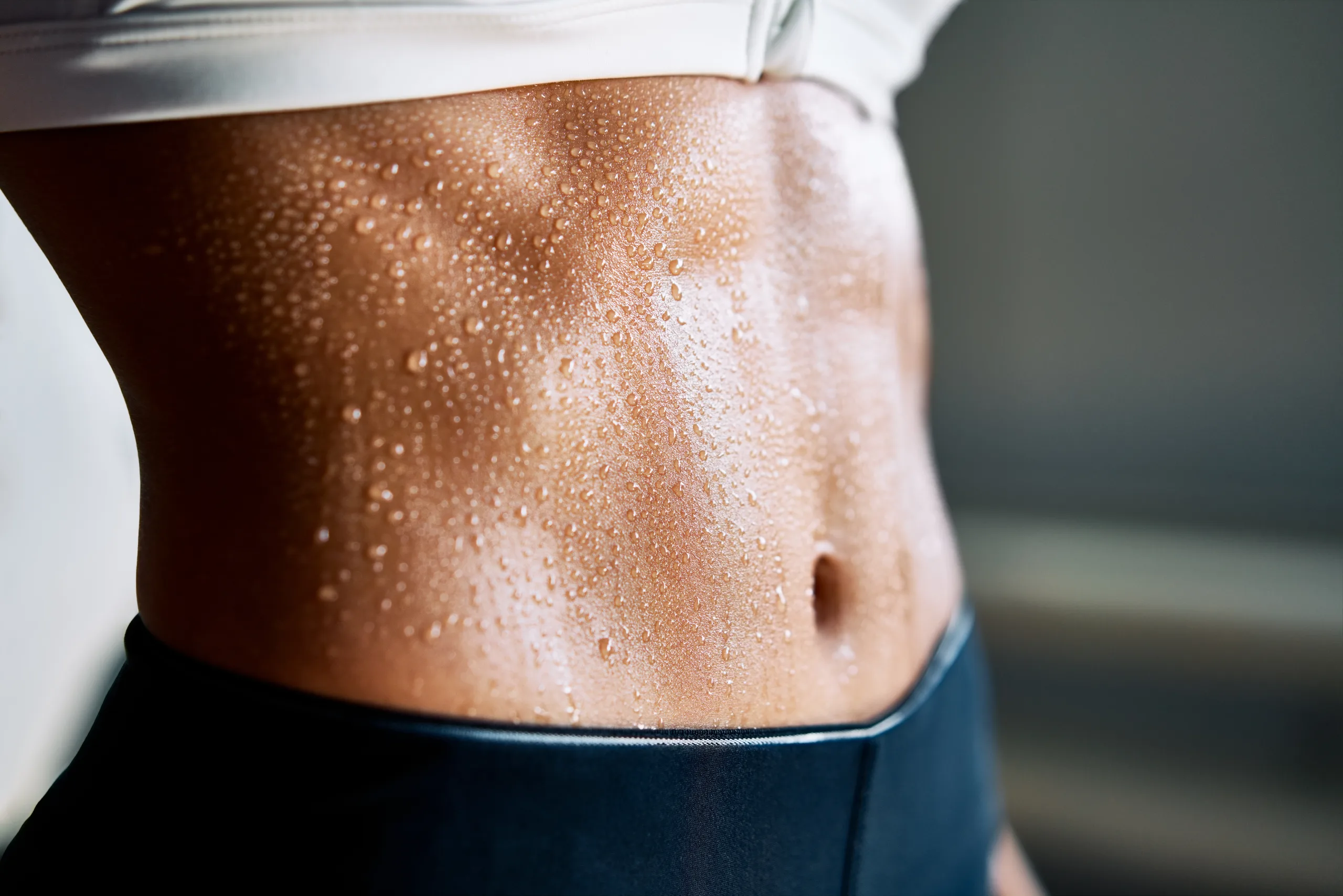 Close up of fit woman torso with sweat on skin after workout. Female with perfect abdomen muscles