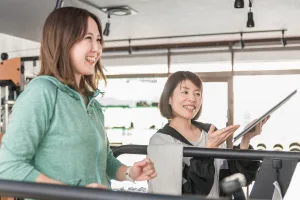 ランニングマシンで走る女性とトレーナー