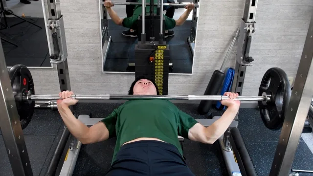 スポーツジムでベンチプレスをする若い男性